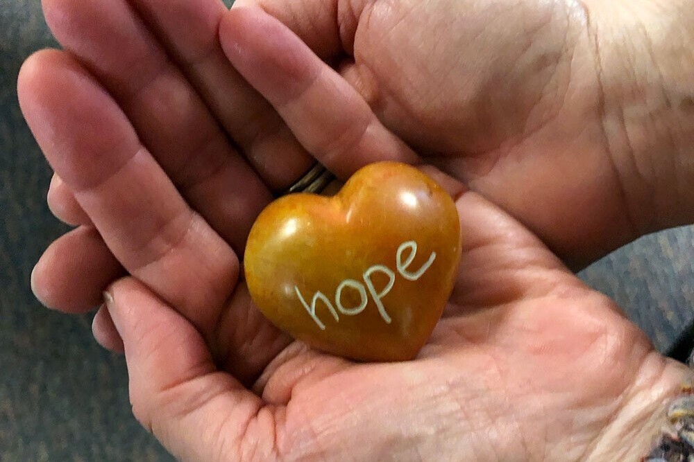 Person holding a heart-shaped rock with the word, 