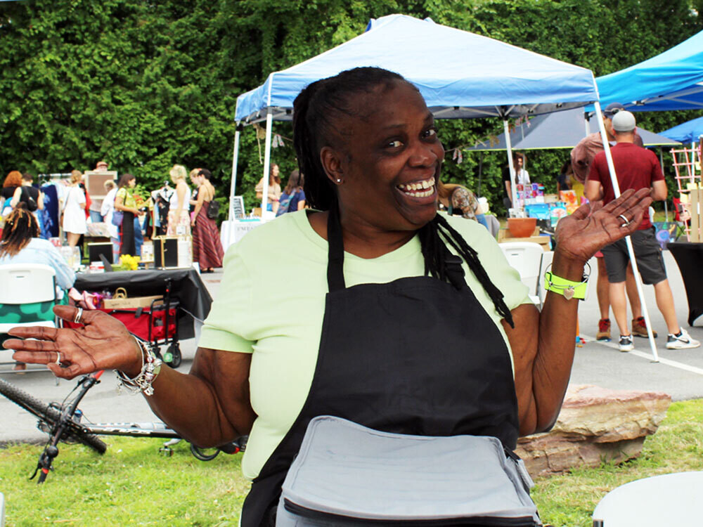 A brown skinned woman wearing an apron smiles widely