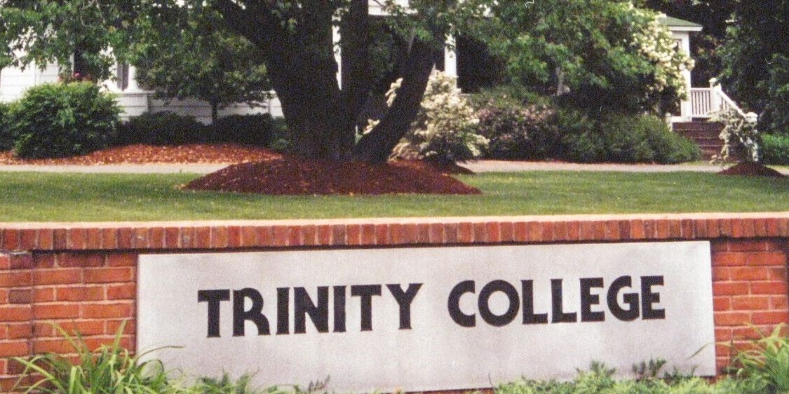 A picture of the Trinity College sign in granite on a brick wall from the 1970s